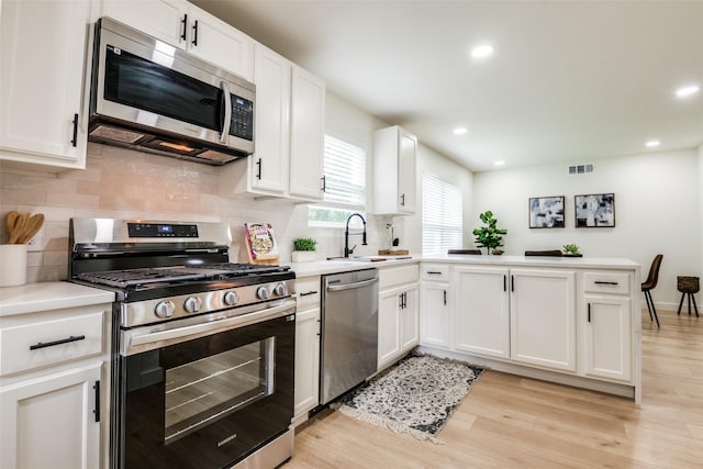 826 Nash St, Rockwall, TX 75087 - kitchen featuring appliances with stainless steel finishes, a peninsula, light wood-type flooring, light countertops, and recessed lighting