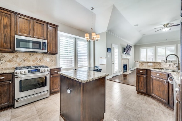 114 Stonecreek Dr, Irving, TX 75063 - kitchen featuring stainless steel appliances, a fireplace with flush hearth, a ceiling fan, decorative backsplash, and vaulted ceiling