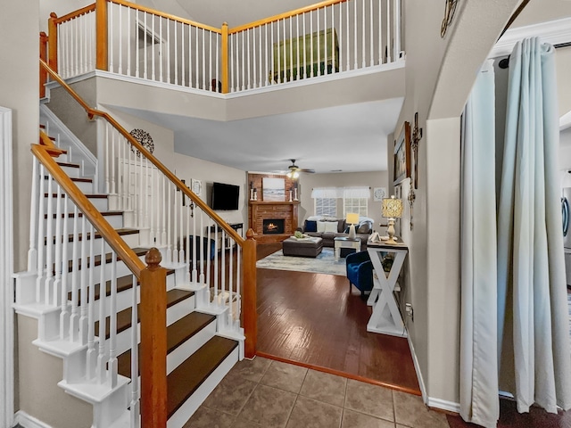 8600 La Quinta Ln, Mckinney, TX 75070 - stairs with a fireplace, a ceiling fan, a towering ceiling, and tile patterned floors