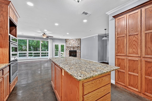 109 Lauren Ln, Pottsboro, TX 75076 - kitchen featuring finished concrete flooring, stainless steel double oven, a ceiling fan, ornamental molding, and a stone fireplace