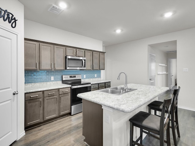3100 Singleton Rd, Forney, TX 75126 - kitchen featuring stainless steel appliances, tasteful backsplash, wood finished floors, a kitchen island with sink, and a breakfast bar area