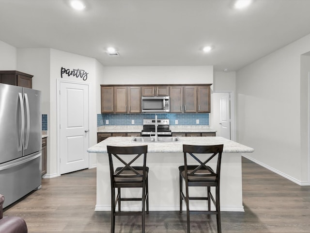 3100 Singleton Rd, Forney, TX 75126 - kitchen with appliances with stainless steel finishes, tasteful backsplash, an island with sink, a breakfast bar, and dark wood-style flooring