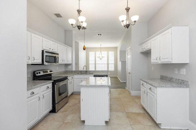 5006 Baton Rouge Blvd, Frisco, TX 75035 - kitchen featuring appliances with stainless steel finishes, a chandelier, a peninsula, white cabinets, and a kitchen island