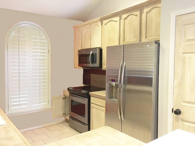 8400 Hickory St Unit 2902, Frisco, TX 75034 - kitchen with stainless steel appliances, light brown cabinets, light countertops, vaulted ceiling, and light tile patterned floors