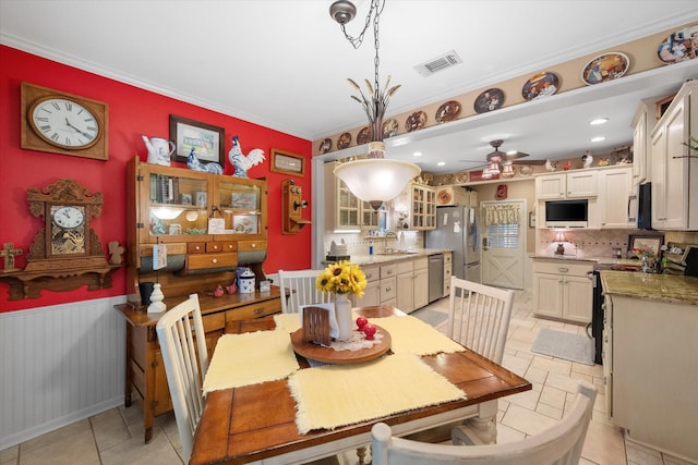 1121 W 3rd Ave, Corsicana, TX 75110 - dining room with wainscoting, ceiling fan, light tile patterned flooring, and ornamental molding