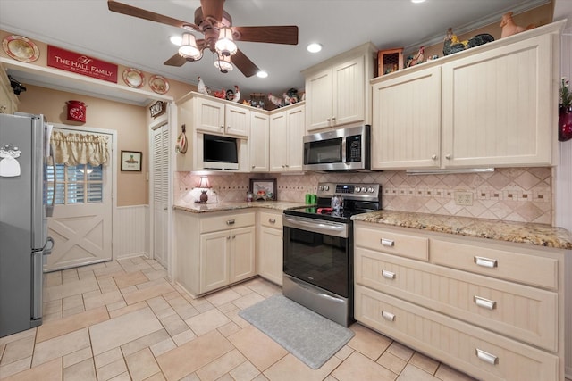 1121 W 3rd Ave, Corsicana, TX 75110 - kitchen with stainless steel appliances, ceiling fan, tasteful backsplash, a wainscoted wall, and light stone countertops