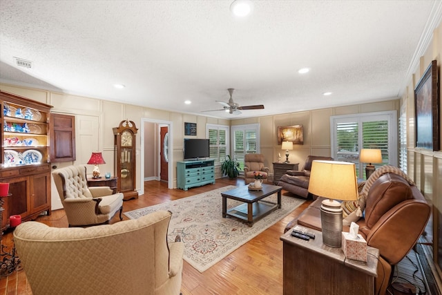1121 W 3rd Ave, Corsicana, TX 75110 - living area featuring a decorative wall, crown molding, ceiling fan, wood finished floors, and a textured ceiling