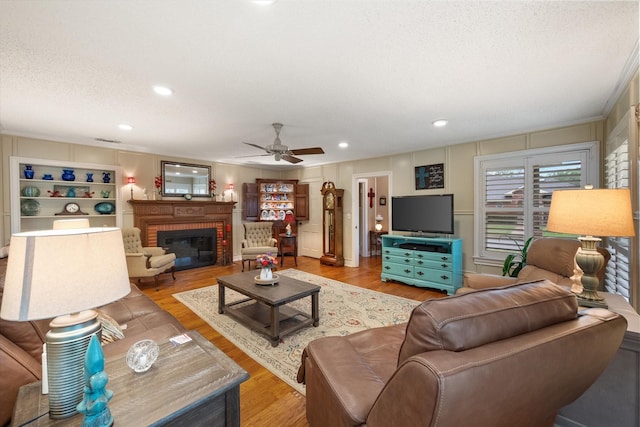 1121 W 3rd Ave, Corsicana, TX 75110 - living area with light wood-style flooring, ceiling fan, a fireplace, a textured ceiling, and recessed lighting