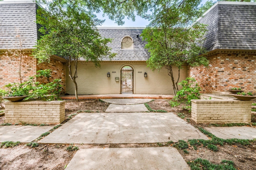 5323 Fleetwood Oaks Ave Unit 256, Dallas, TX 75235 - property entrance featuring mansard roof, a shingled roof, and brick siding