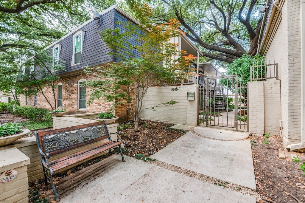 5323 Fleetwood Oaks Ave Unit 256, Dallas, TX 75235 - view of side of home with mansard roof, a gate, brick siding, and roof with shingles