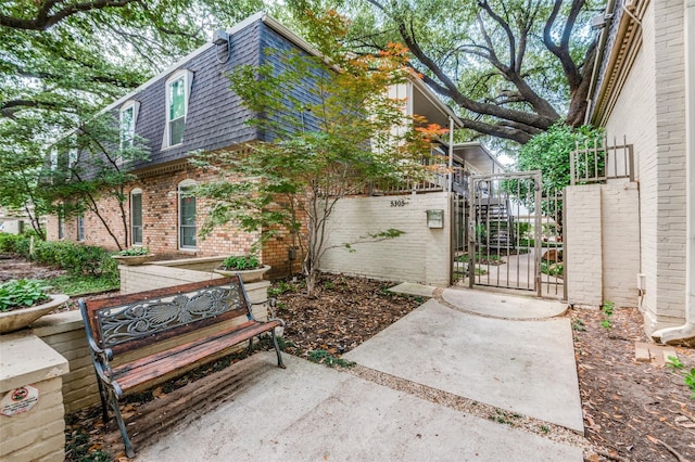 5323 Fleetwood Oaks Ave Unit 256, Dallas, TX 75235 - view of side of home with mansard roof, a gate, brick siding, and roof with shingles
