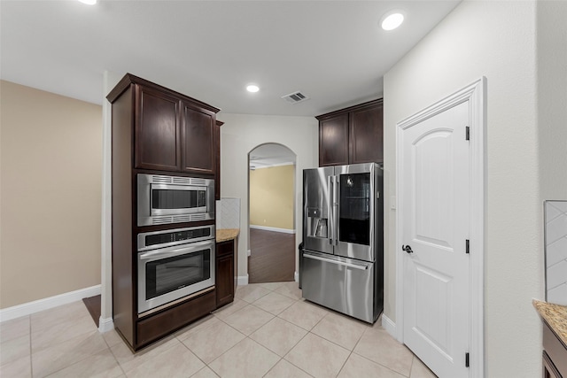 641 Woodridge Dr, Oak Point, TX 75068 - kitchen featuring stainless steel appliances, arched walkways, dark brown cabinetry, light tile patterned floors, and recessed lighting