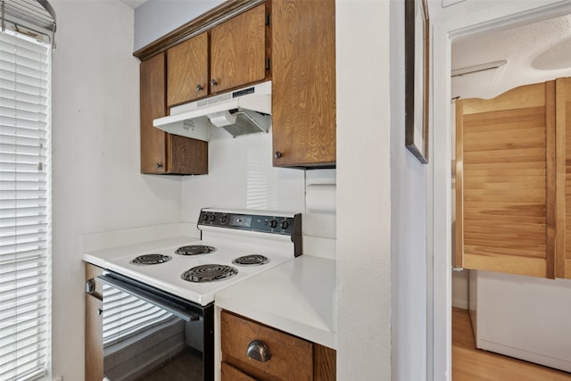 9999 Boat Club Rd Unit 107, Fort Worth, TX 76179 - kitchen featuring electric range, under cabinet range hood, brown cabinetry, and light countertops