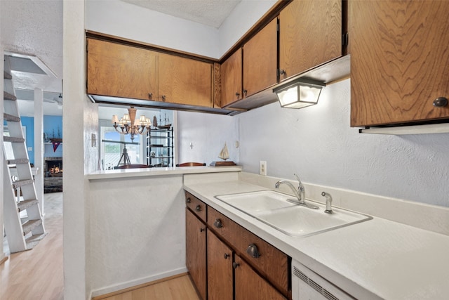 9999 Boat Club Rd Unit 107, Fort Worth, TX 76179 - kitchen with light wood finished floors, light countertops, brown cabinets, a chandelier, and a textured wall
