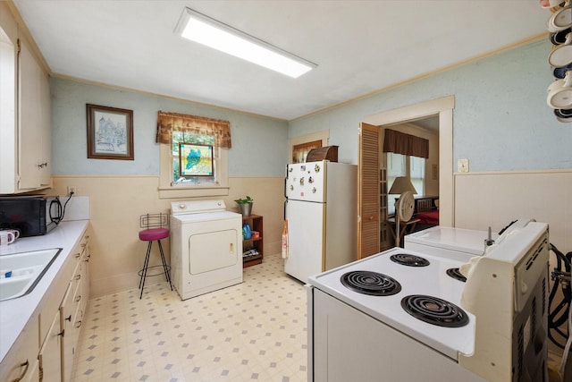 110 Woodland Ave, Corsicana, TX 75110 - kitchen featuring washer / dryer, white appliances, light floors, wainscoting, and light countertops