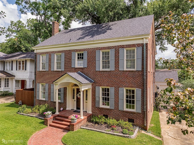 539 Atkins Ave, Shreveport, LA 71104 - georgian-style home with a chimney, brick siding, a front yard, and a shingled roof