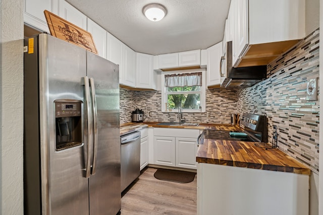 1321 S Lamar St, Weatherford, TX 76086 - kitchen with stainless steel appliances, butcher block counters, decorative backsplash, light wood-style floors, and white cabinetry