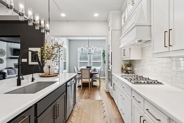 7709 Waterside, The Colony, TX 75056 - kitchen featuring appliances with stainless steel finishes, custom exhaust hood, light countertops, white cabinets, and a chandelier