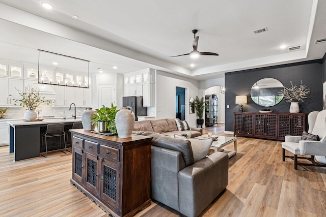 7709 Waterside, The Colony, TX 75056 - living area featuring a raised ceiling, light wood-type flooring, a ceiling fan, recessed lighting, and arched walkways