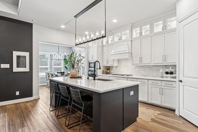 7709 Waterside, The Colony, TX 75056 - kitchen with custom range hood, stainless steel appliances, a center island with sink, decorative backsplash, and a breakfast bar area