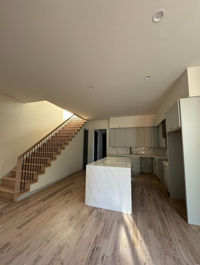 906 S Ewing Ave, Dallas, TX 75203 - kitchen featuring light wood finished floors, a kitchen island, gray cabinetry, light stone countertops, and recessed lighting