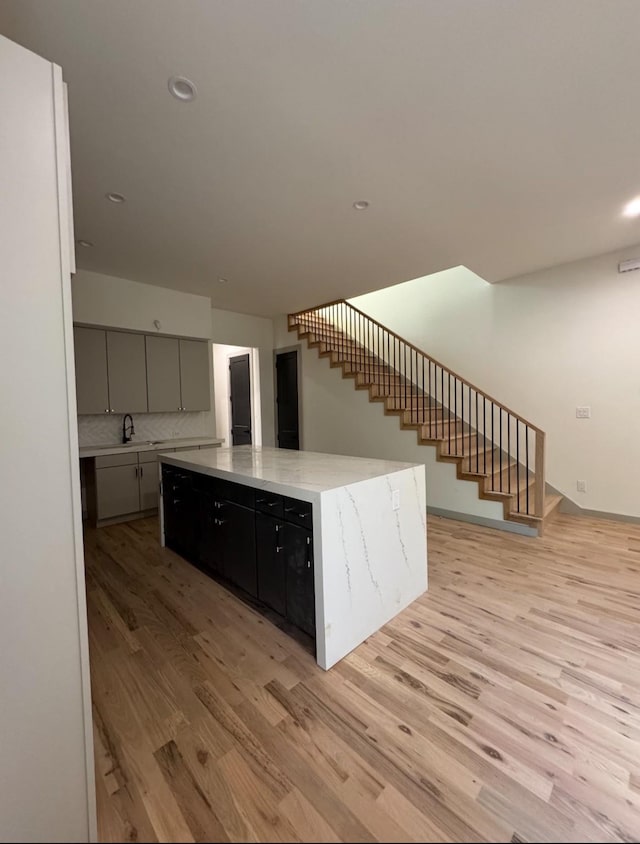 908 S Ewing Ave, Dallas, TX 75203 - kitchen featuring light wood-style flooring, a spacious island, recessed lighting, backsplash, and gray cabinets