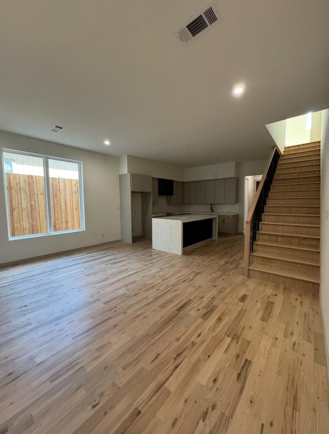 908 S Ewing Ave, Dallas, TX 75203 - unfurnished living room featuring light wood-style flooring, stairway, and recessed lighting