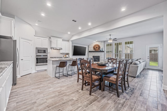 14840 Nightmist Rd, Aledo, TX 76008 - dining room featuring a ceiling fan, a fireplace, light wood-style floors, recessed lighting, and vaulted ceiling