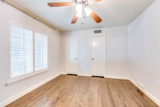 6823 Walnut Hill Ln, Dallas, TX 75230 - unfurnished bedroom featuring wood finished floors, multiple windows, and ceiling fan