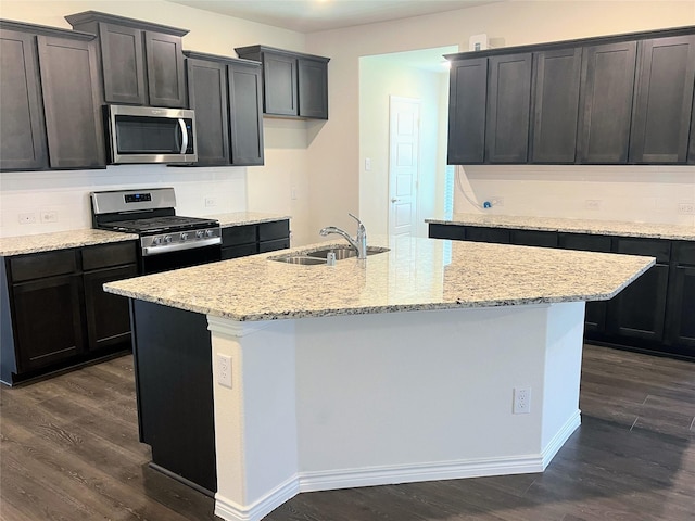255 Carolina Trce, Fate, TX 75189 - kitchen with stainless steel appliances, dark wood-style flooring, a kitchen island with sink, and light stone countertops