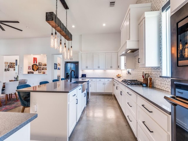 641 Cox Rd, Waxahachie, TX 75167 - kitchen with decorative backsplash, appliances with stainless steel finishes, finished concrete floors, white cabinetry, and a center island with sink