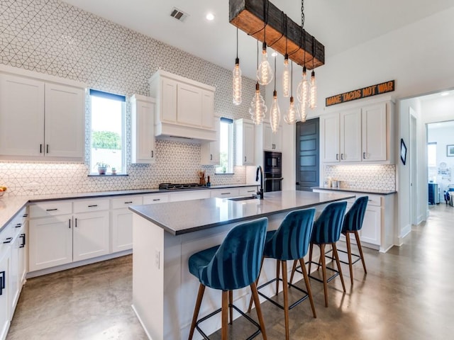 641 Cox Rd, Waxahachie, TX 75167 - kitchen with black appliances, tasteful backsplash, finished concrete flooring, white cabinets, and a kitchen bar