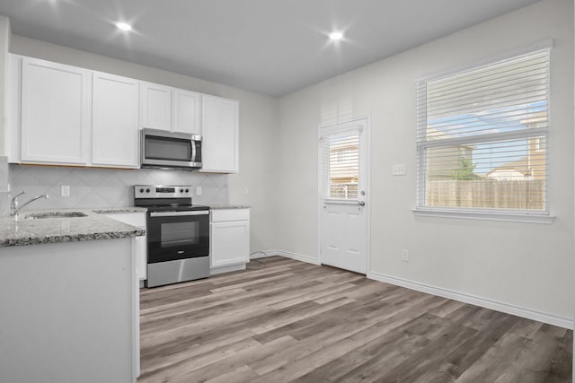 8313 White Pine Dr, Fort Worth, TX 76123 - kitchen featuring stainless steel appliances, white cabinets, light wood-style flooring, backsplash, and light stone countertops
