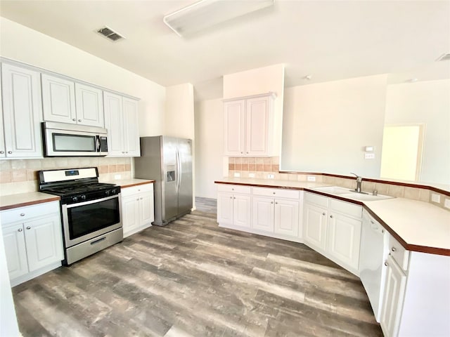 2717 Lumina Dr, Little Elm, TX 75068 - kitchen with stainless steel appliances, a peninsula, decorative backsplash, light wood-style flooring, and white cabinetry