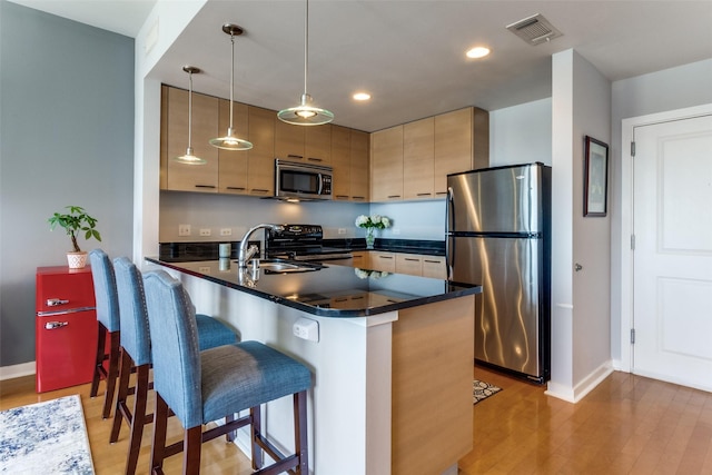 1200 Main St Unit 1402, Dallas, TX 75202 - kitchen featuring appliances with stainless steel finishes, dark countertops, a peninsula, a breakfast bar, and recessed lighting