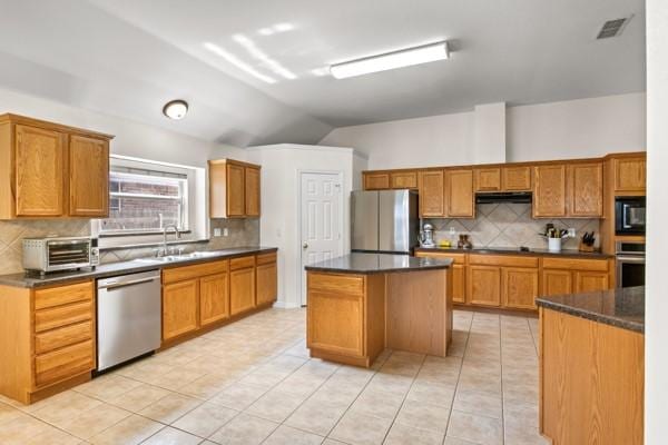 521 Willowview Dr, Saginaw, TX 76179 - kitchen with appliances with stainless steel finishes, lofted ceiling, dark countertops, and decorative backsplash