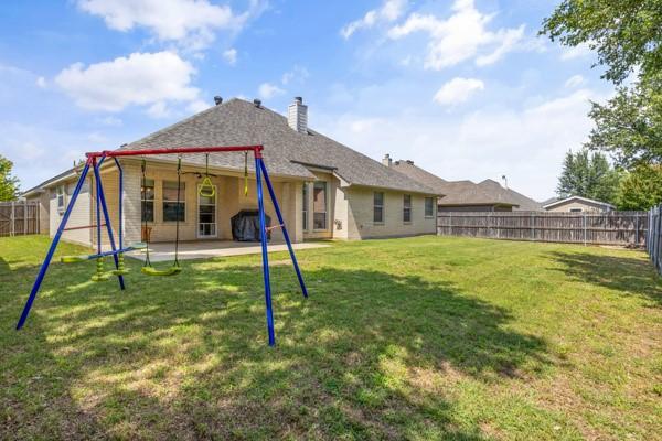 521 Willowview Dr, Saginaw, TX 76179 - back of house featuring a fenced backyard, a patio, a chimney, and a playground