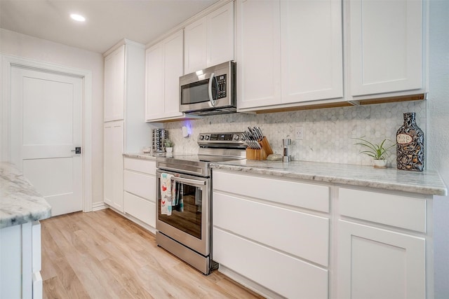 705 Tracy Dr, Azle, TX 76020 - kitchen with appliances with stainless steel finishes, decorative backsplash, white cabinetry, light wood-type flooring, and light stone counters
