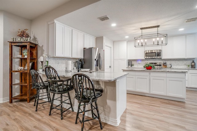705 Tracy Dr, Azle, TX 76020 - kitchen featuring appliances with stainless steel finishes, a peninsula, decorative backsplash, white cabinets, and recessed lighting