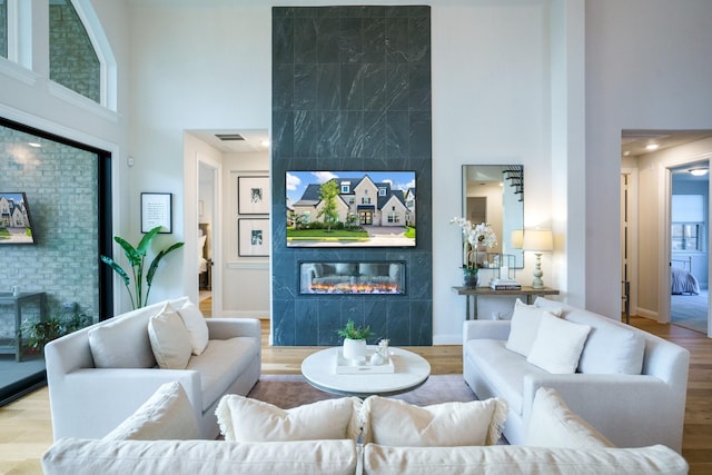 3915 Lochwood Dr, Rowlett, TX 75088 - living area featuring a tiled fireplace, a towering ceiling, wood finished floors, and an accent wall