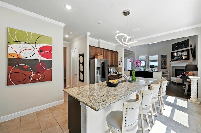 2711 Fleur De Lis Ln, Grand Prairie, TX 75054 - kitchen with high end refrigerator, ornamental molding, recessed lighting, a kitchen breakfast bar, and light stone countertops