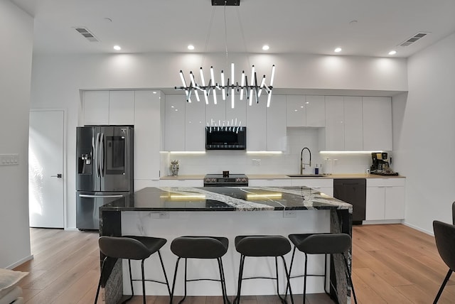 2001 N Prairie Ave Unit 106, Dallas, TX 75204 - kitchen with appliances with stainless steel finishes, modern cabinets, a kitchen breakfast bar, tasteful backsplash, and recessed lighting