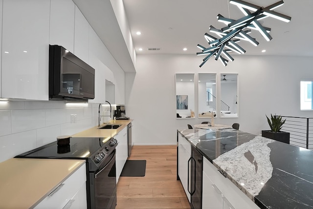 2001 N Prairie Ave Unit 106, Dallas, TX 75204 - kitchen featuring black appliances, light wood-style floors, modern cabinets, white cabinetry, and recessed lighting