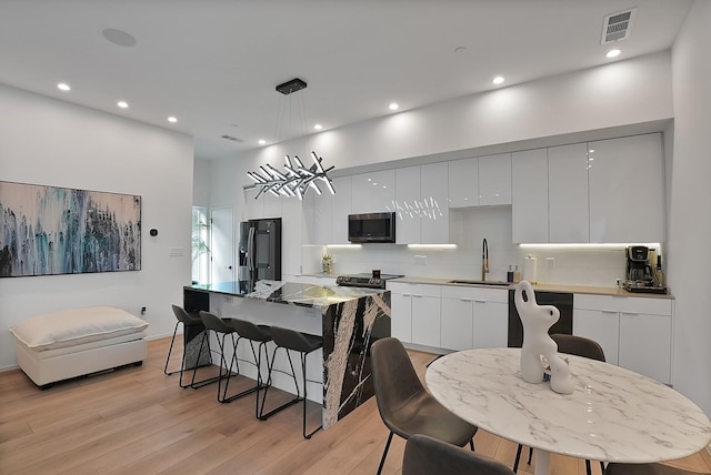 2001 N Prairie Ave Unit 106, Dallas, TX 75204 - kitchen with stainless steel microwave, modern cabinets, dishwasher, a breakfast bar area, and recessed lighting