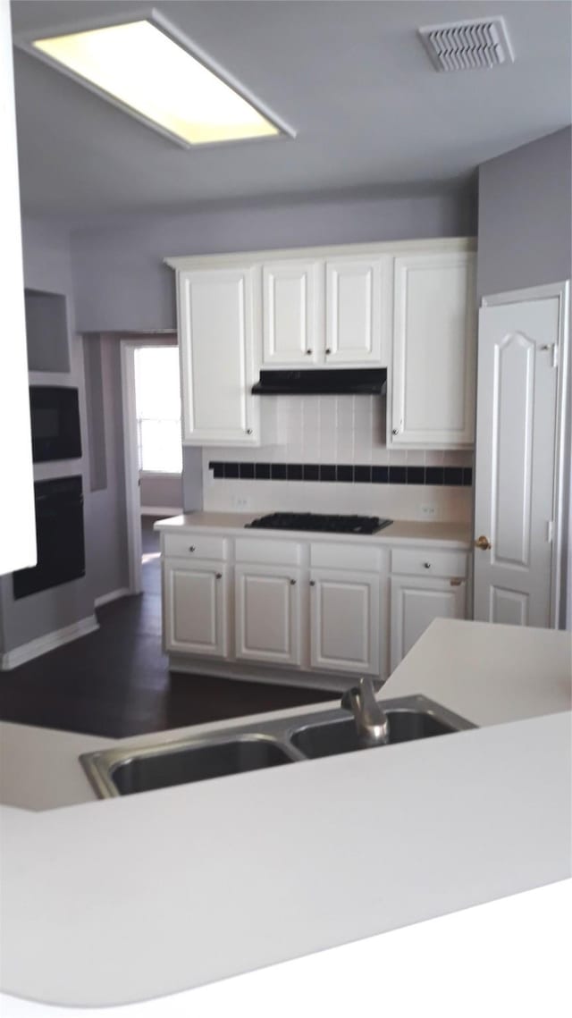 2017 Greenfield Ln, Allen, TX 75013 - kitchen featuring appliances with stainless steel finishes, white cabinets, under cabinet range hood, tasteful backsplash, and light countertops