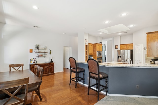 2020 El Camino Dr, Fort Worth, TX 76177 - kitchen featuring stainless steel appliances, a peninsula, light stone counters, recessed lighting, and light wood-style floors