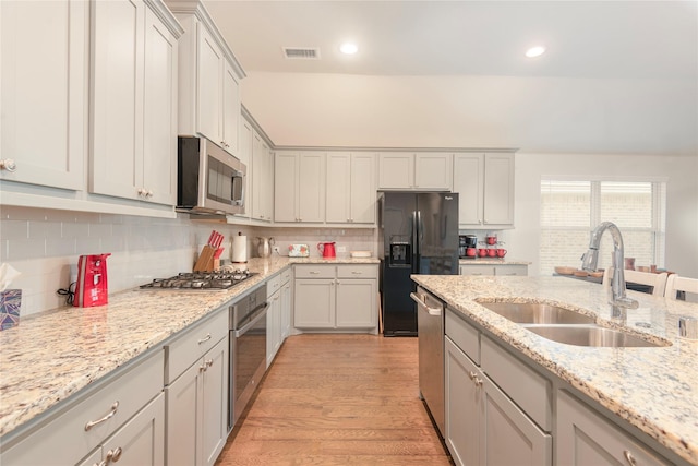 873 Mildren Ln, Fate, TX 75087 - kitchen with stainless steel appliances, decorative backsplash, light wood finished floors, recessed lighting, and light stone countertops
