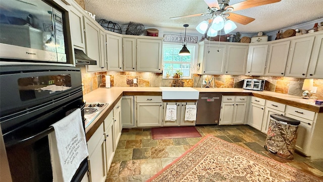 1705 14th St, Brownwood, TX 76801 - kitchen featuring appliances with stainless steel finishes, stone tile floors, a textured ceiling, backsplash, and under cabinet range hood