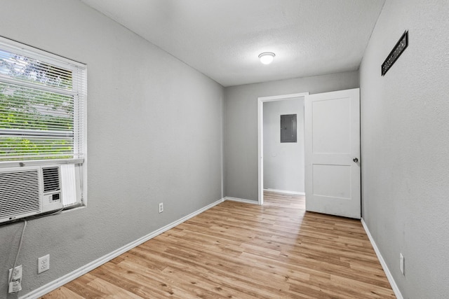 701 W Hull St Unit 101-2, Denison, TX 75020 - unfurnished room featuring electric panel, light wood finished floors, a textured ceiling, and a textured wall