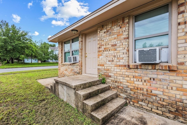 701 W Hull St Unit 101-2, Denison, TX 75020 - view of exterior entry with brick siding, a lawn, and cooling unit